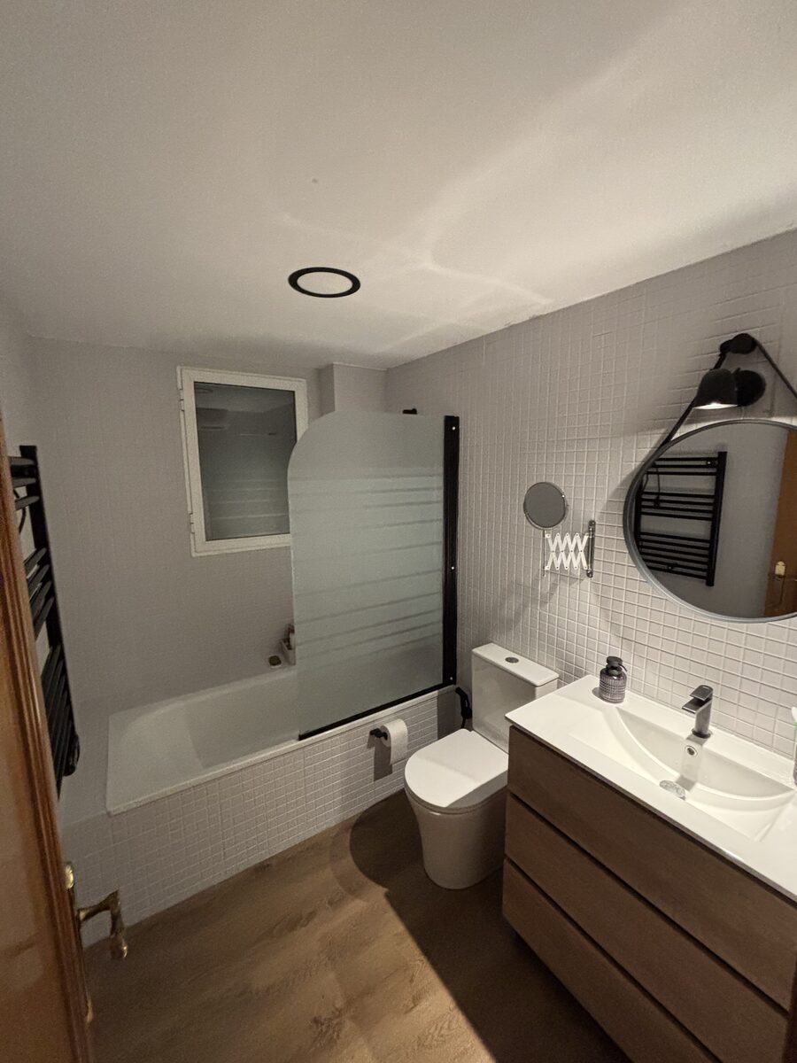 Baño con bañera y espejo redondo